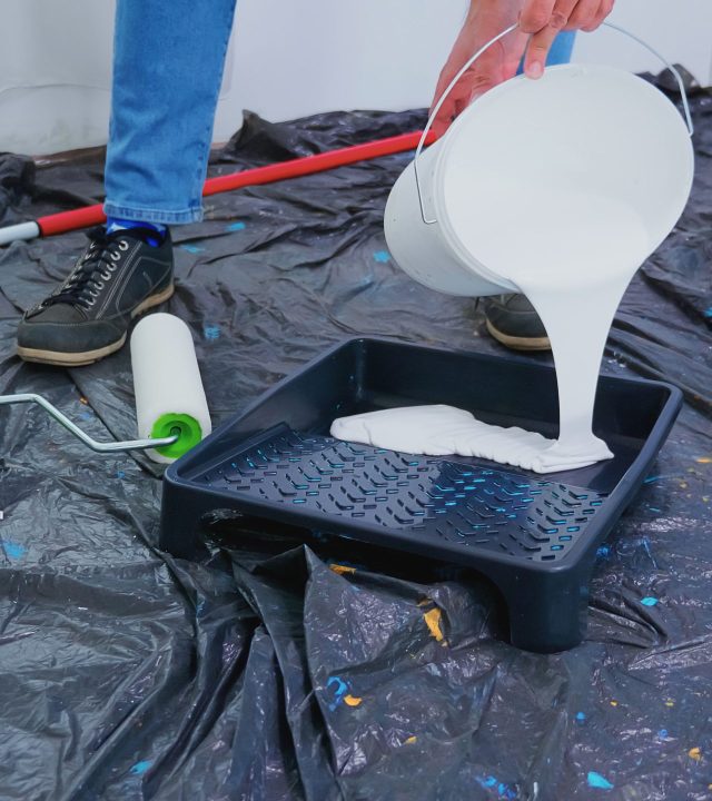 Handyman pouring white paint for home renovation. Couple in apartment flat, repair and makeover